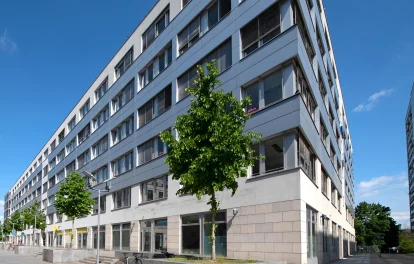 Außenansicht vom Trigon Office in Dresden mit blauem Himmel und davorstehenden Bäumen.