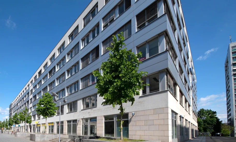 Außenansicht vom Trigon Office in Dresden mit blauem Himmel und davorstehenden Bäumen.