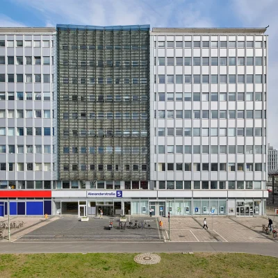 Das Bild zeigt die Vorderansicht eines modernen Bürogebäudes nahe dem Alexanderplatz in Berlin mit Glasfassade und klarer Linienführung.