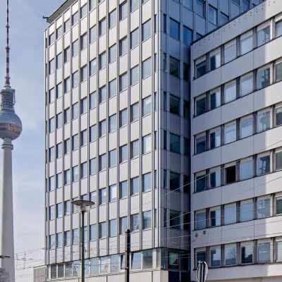 Das Foto zeigt ein Bürogebäude in Berlin mit Blick auf den Fernsehturm und vorbeifahrender Tram an der Alexanderstraße.