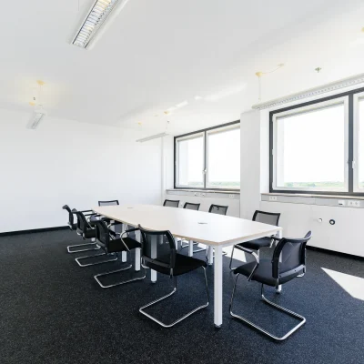 Der helle Meetingraum mit Fensterfront bietet Platz für mehrere Personen am Konferenztisch.