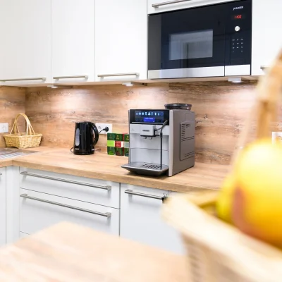 Die moderne Büroküche ist mit einer Kaffeemaschine, Mikrowelle und Holzarbeitsplatte ausgestattet.