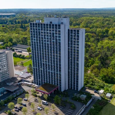Luftaufnahme der Arabella Offices Frankfurt mit Blick auf das Hochhaus, angrenzenden Wald und den Horizont.