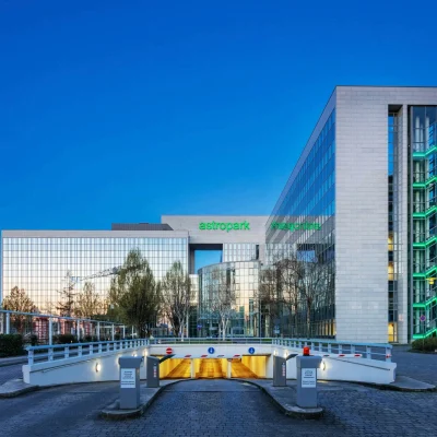 Die Zufahrt zur Tiefgarage des Astroparks in Frankfurt in der Abenddämmerung mit spiegelnder Glasfassade.