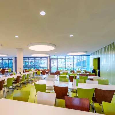 Die moderne Kantine eines Bürogebäudes in Frankfurt ist großzügig gestaltet und bietet zahlreiche Sitzplätze bei viel Tageslicht.