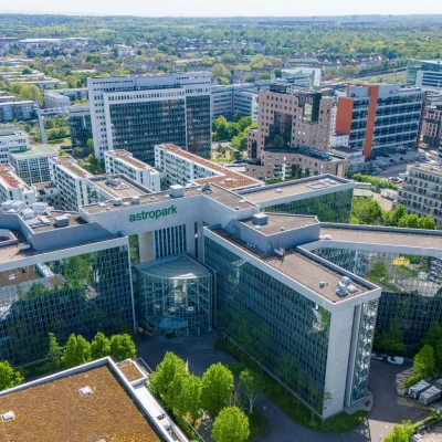 Luftaufnahme des Astropark Bürokomplexes in Frankfurt mit umliegender Stadt und viel Grünfläche.