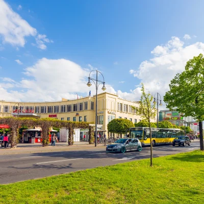 Das Bild zeigt den zentralen Haupteingang des Einkaufszentrums Der Clou in Berlin mit umliegendem Platz und Geschaeften.