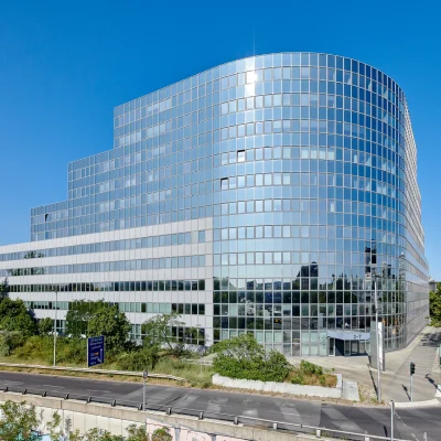 Moderne Gesamtansicht eines Bürogebäudes mit Glasfassade in Berlin bei klarem Himmel.