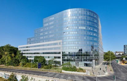 Moderne Gesamtansicht eines Bürogebäudes mit Glasfassade in Berlin bei klarem Himmel.