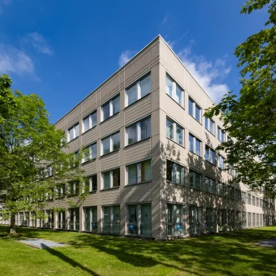 Das Bild zeigt die Außenansicht eines modernen Bürogebäudes in Gelsenkirchen mit Grünanlagen im Gewerbepark.