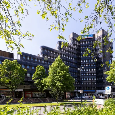 Blick auf ein Bürohochhaus in Dortmund mit Glasfassade und umliegender Grünanlage an der Straße.
