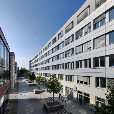 Das Bild zeigt die Außenansicht des Trigon Office in Dresden mit moderner Fassade entlang einer Fußgängerzone und angrenzender Bebauung.