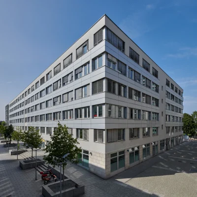 Ein modernes Bürogebäude in Dresden mit Glasfassade an einer Straßenecke in der Fußgängerzone.