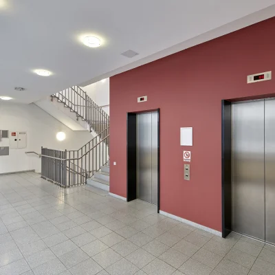 Das Bild zeigt den Eingangsbereich des Trigon Office in Dresden mit zwei Edelstahlaufzügen und Treppenaufgang.