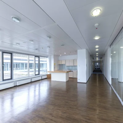 Zu sehen ist ein heller Büroraum mit Fensterfront, Teeküche und Essbereich für Pausen.