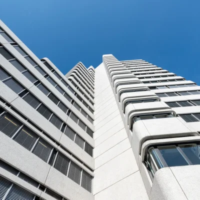 Froschperspektive der Betonfassade mit umlaufenden Balkonen vor blauem Himmel