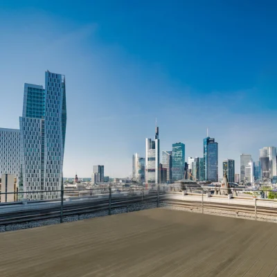 Das Bild zeigt eine Dachterrasse mit Blick auf die Skyline von Frankfurt und mehrere moderne Hochhäuser im Hintergrund.