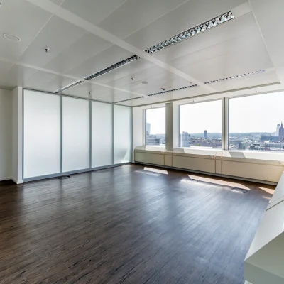 Das Bild zeigt eine moderne Bürofläche im HAT64 Frankfurt mit dunklem Holzboden, großen Fenstern und Ausblick über die Stadt.