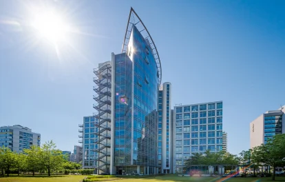 Das Bild zeigt die Außenansicht des SIGMA Hochhauses in Frankfurt mit moderner Glasfassade bei Sonnenschein.