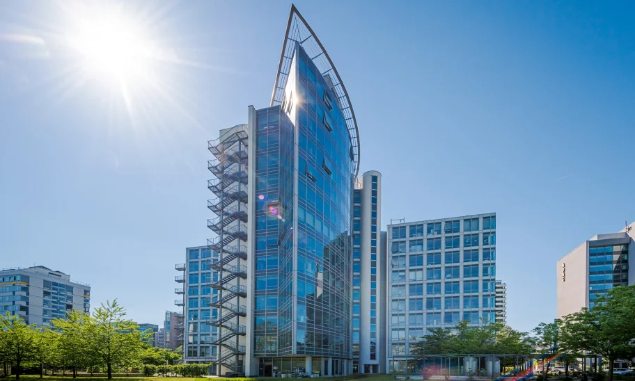 Das Bild zeigt die Außenansicht des SIGMA Hochhauses in Frankfurt mit moderner Glasfassade bei Sonnenschein.