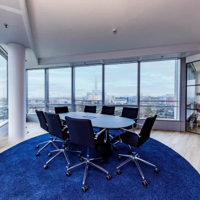 Das Bild zeigt ein modernes Eckbüro im SIGMA Frankfurt mit Glasfront und Ausblick über die Stadt, ausgestattet mit rundem Tisch und Teppichboden.