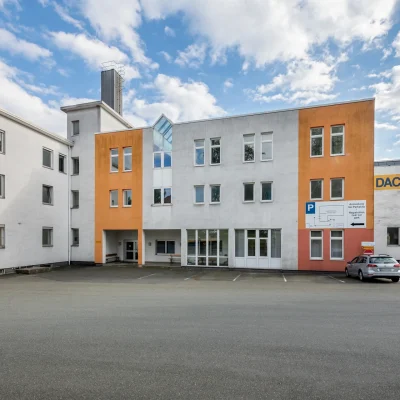 Innenansicht einer modernen Lagerhalle mit gestapelten Kartons und Paletten in Regalen.