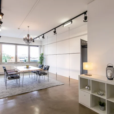 Ein heller Meetingraum in Hannover mit modernem Tisch, Stühlen, Fensterfront und dekorativer Einrichtung.