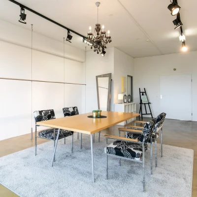 Design-Meetingraum mit großem Holztisch, Teppich und dekorativer Beleuchtung in einem Büro in Hannover.