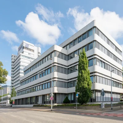 Das Bild zeigt die moderne Außenansicht eines Bürogebäudes in Hannover mit klarer Architektur und großen Fensterflächen.