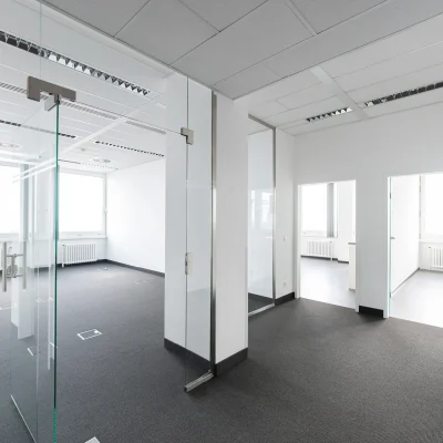 Leerer Büroraum in einem hohen Bürogebäude in Hannover mit großen Fenstern und strukturiertem Teppichboden.