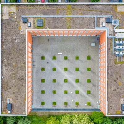 Das Bild zeigt eine Luftaufnahme eines Bürogebäudes in Teltow bei Berlin mit einem begrünten Innenhof in U-Form.