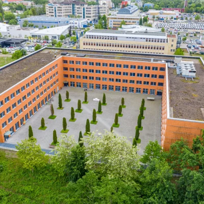 Das Bild zeigt eine weite Luftaufnahme eines Bürokomplexes in Teltow bei Berlin mit großem Innenhof und umliegender Stadtstruktur.
