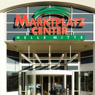 Abgebildet ist der Haupteingang des Marktplatz Centers Berlin-Hellersdorf mit Glasfassade und großem Logo.