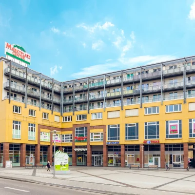 Das Bild zeigt die Fassadenansicht des Marktplatz Centers Berlin-Hellersdorf mit Wohnungen über den Geschäften.