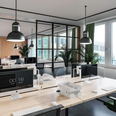 Offener Arbeitsbereich im Industrial-Style mit vielen Schreibtischen, Computern und grünen Pflanzen in einem Münchner Bürogebäude.