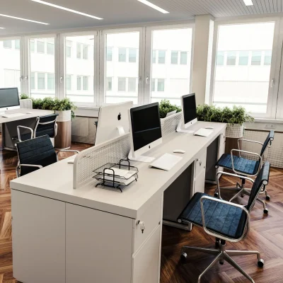 Das Bild zeigt einen modernen Büroraum im Next Office München mit Parkettboden, Schreibtischen, Monitoren, ergonomischen Stühlen und vielen Pflanzen vor großen Fenstern.