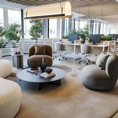 Ein modernes Großraumbüro mit Lounge-Bereich, Designmöbeln, Pflanzen und Arbeitsplätzen in München.