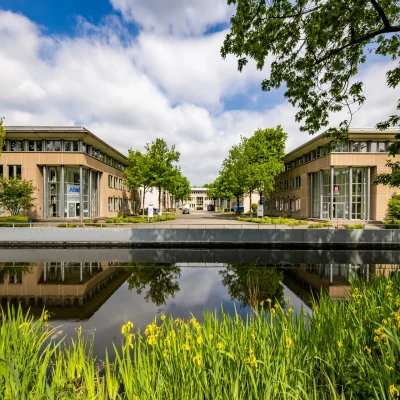 Die Außenansicht des Bürohauses Nordstern Offices zeigt moderne Gebäude mit Glasfassade, einem Teich mit Spiegelung und umliegender Grünanlage.