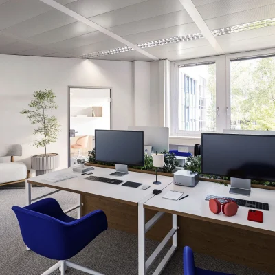 Ein modernes Großraumbüro mit zwei Schreibtischen, Monitoren, blauen Bürostühlen, großen Fenstern und dekorativen Pflanzen.