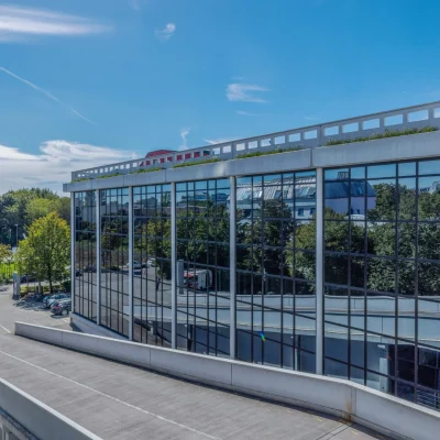 Ein moderner Gebäudekomplex mit verspiegelter Glasfassade in urbaner Umgebung.