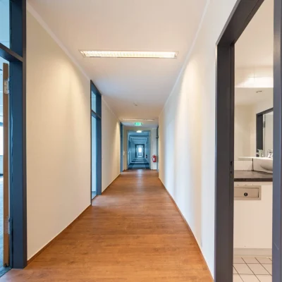 Langer Flur einer Büroetage in Berlin mit Holzboden und Zugang zu Büroräumen.