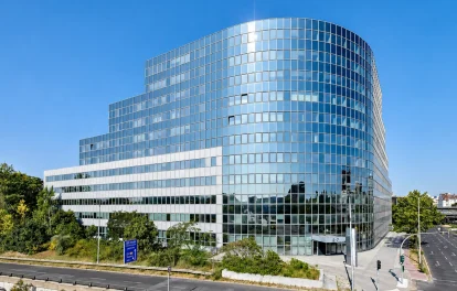 Außenansicht des Platinum Office am Sachsendamm 2–7 in Berlin mit geschwungener Glasfassade an einer Straßenkreuzung