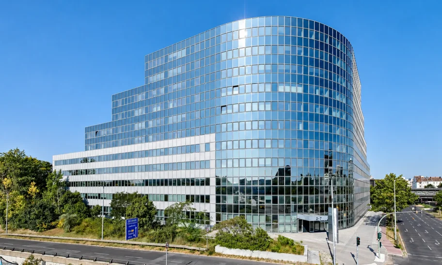Außenansicht des Platinum Office am Sachsendamm 2–7 in Berlin mit geschwungener Glasfassade an einer Straßenkreuzung