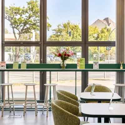 Helle Lounge im Platinum Office am Sachsendamm in Berlin mit grünen Sesseln, Fensterbar und hoher Glasfront