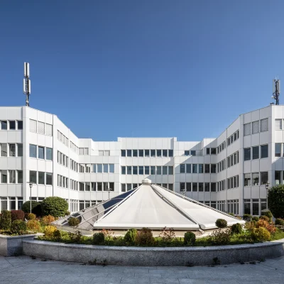Der Innenhof eines modernen Bürogebäudes mit Glasdach in München ist von einer weißen Gebäudefassade umgeben.