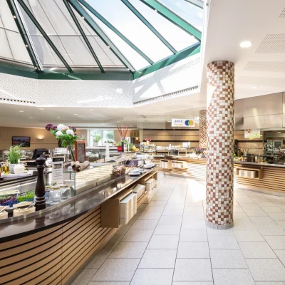 Die moderne Kantine im Münchner Quadrum zeigt einen hellen Essbereich mit Glasdach, verschiedenen Buffets und dekorativen Elementen.