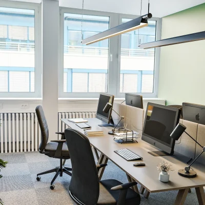 Das Bild zeigt ein modernes Büro im Quadrum-Gebäude in München mit großen Fenstern, ergonomischen Arbeitsplätzen und Pflanzen zur Raumgestaltung.