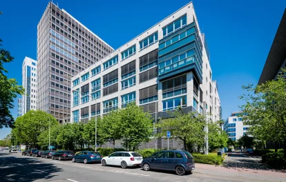 Das Bild zeigt ein modernes Bürohochhaus in Frankfurt mit Glasfassade und benachbarter Hochhausarchitektur.