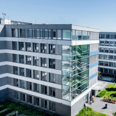 Bürogebäude-Komplex mit Glasfassade, verglastem Treppenhausturm und begrüntem Innenhof bei Tageslicht