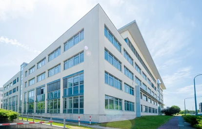 Eckansicht eines modernen Bürogebäudes mit Glasfassade und städtischer Umgebung.
